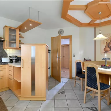A modern kitchen with wooden furniture and a cozy dining area. The room is bright and well-structured.