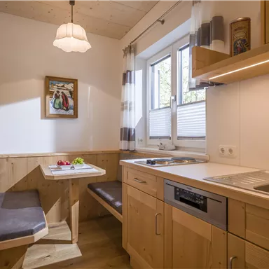 A bright kitchen with wood paneling and a small dining area. There is a window that lets in a lot of light, and a modern kitchen setup.