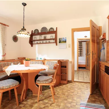 A cozy kitchen with a round table and wooden chairs. Bright walls and an open ambiance create an inviting atmosphere.