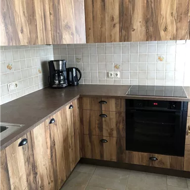 A modern kitchen with wooden furniture and appliances. The room has a bright, cozy atmosphere.