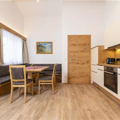 A modern kitchen with a dining table and wooden bench. Brightly lit, with a practical design and a cozy atmosphere.