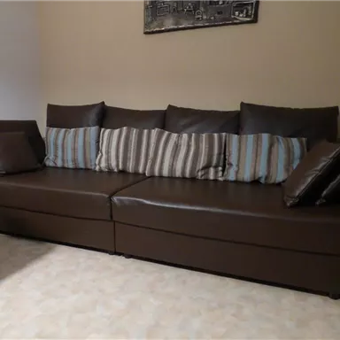 A comfortable brown sofa with striped and solid-colored cushions. The background is kept in neutral colors.