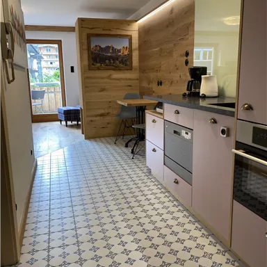 Eine moderne Küche mit hellen Möbeln und einem schönen Fliesenboden. An der Wand befindet sich ein hochwertiges Holz-Element.