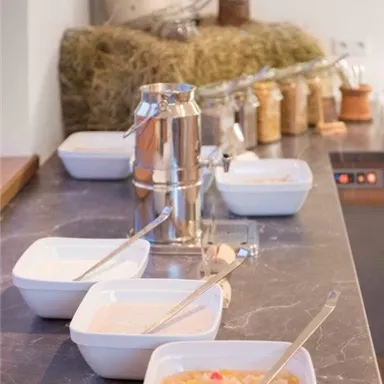 A selection of various bowls with food on a table. In the background, some natural ingredients and utensils are visible.