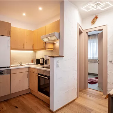 A modern kitchen with wooden cabinets and appliances. In the background, an image of a mountain landscape is visible.