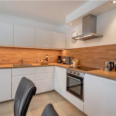 A modern kitchen with white cabinets and a wooden countertop. It is well-equipped with cooking appliances and has an inviting atmosphere.