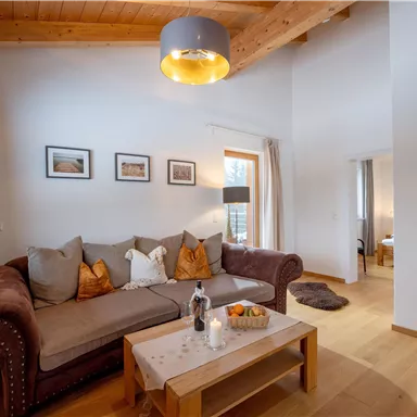 A cozy living room with a brown couch and a wooden table.
Bright walls and wooden ceilings create a warm atmosphere.