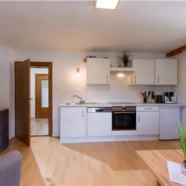 A modern kitchen with light cabinets and wooden flooring. The space is designed to be friendly and inviting.