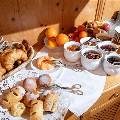 Ein reichhaltiges Frühstücksbuffet mit verschiedenen Backwaren, frischem Obst und verschiedenen Marmeladen. Die Präsentation ist hell und einladend.