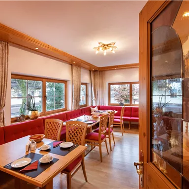 Ein einladendes Restaurant mit roten Bänken und Holzdekor. Auf den Tischen liegen Geschirr und Besteck, bereit für die Gäste.