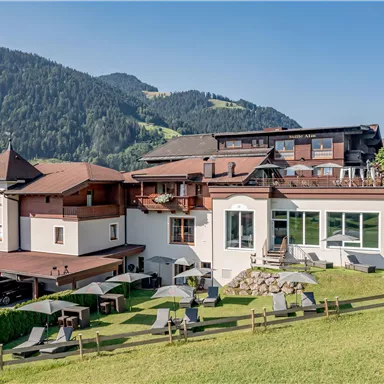 A modern hotel nestled among green hills and mountains. The surroundings are peaceful and inviting, perfect for relaxation and enjoying nature.