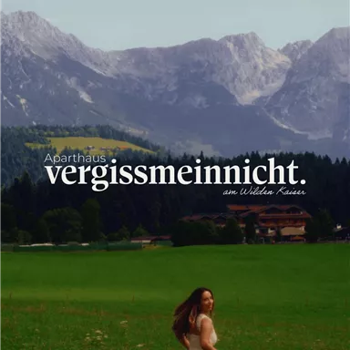 Ein schönes altes Gebäude inmitten einer malerischen Berglandschaft. Im Vordergrund steht eine Frau in einem langen Kleid.