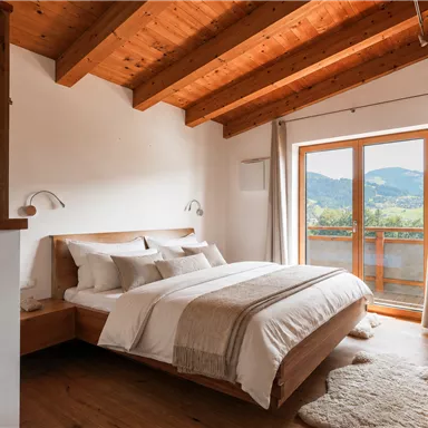 A modern bedroom with a wooden ceiling and large windows. The room is bright and inviting for relaxation and offers a beautiful view of the landscape.