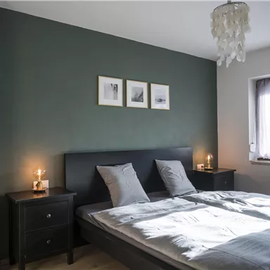 A modern bedroom with a double bed and soft colors. There are nightstands with lamps and pictures on the wall.