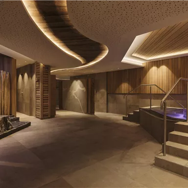 Ein modernes Spa mit sanfter Beleuchtung und Holzvertäfelungen. Der Bereich bietet eine entspannende Atmosphäre mit einer Treppe zu einem Innenpool.