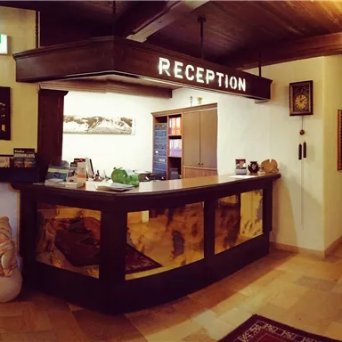 An inviting reception area with a wooden counter and warm lighting. Decorative pictures and information for guests are displayed on the walls.