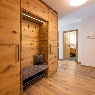 A modern hallway with warm wooden furniture and a comfortable seating area. The design creates an inviting atmosphere.