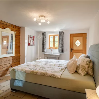 Ein gemütliches Schlafzimmer mit einem großen Bett und hellem Holzdekor. Das Zimmer ist gut beleuchtet und lädt zum Entspannen ein.