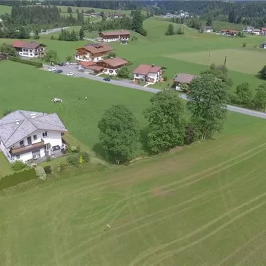 A picturesque landscape with several houses and lush green meadows. The surroundings feel calm and rural.