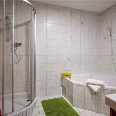 A modern bathroom with a shower and a bathtub. The room has bright tiles and a clean, friendly atmosphere.