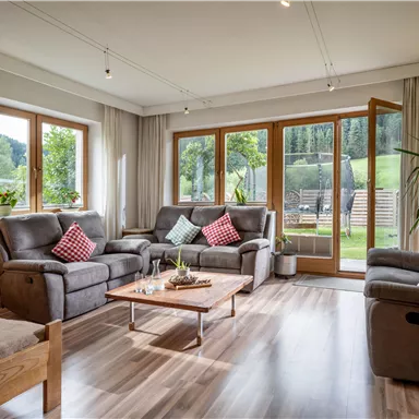 A modern living room with comfortable sofas and plenty of natural light.
Large windows provide a view of the green landscape.