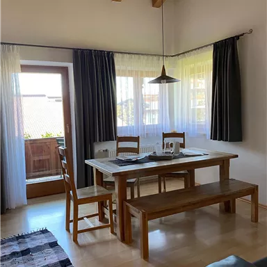 A bright, inviting dining room with a wooden table and chairs. Large windows provide plenty of daylight and a pleasant atmosphere.
