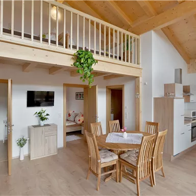 Eine moderne Ferienwohnung mit Holzdekor und einem offenen Wohnbereich. Der Essplatz ist gemütlich eingerichtet und die Küche ist gut ausgestattet.