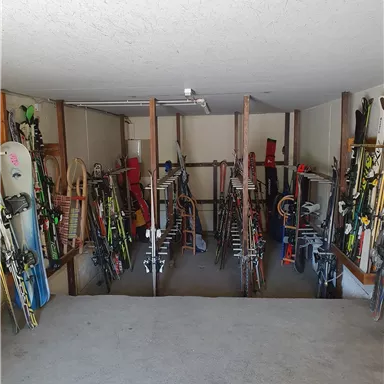 An orderly stockroom with various skis and snowboards. The equipment is neatly arranged and ready for the next trip.