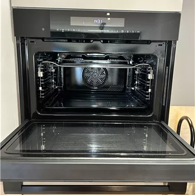 A modern oven with a clear interior. The appliance has a digital display and is in an elegant black color.