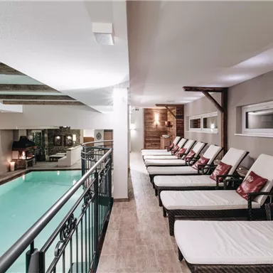 A relaxing wellness area with loungers and a swimming pool. The space is modernly designed and offers a cozy atmosphere.