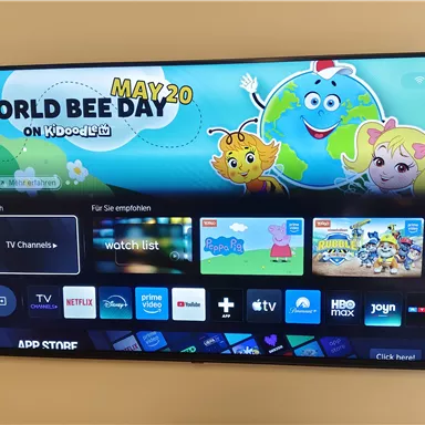 A television with a colorful screen that promotes the "World Bee Day". There are various apps and recommendations on the user interface.