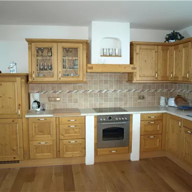 A cozy kitchen with wooden furniture and modern design. There is a stove and a large countertop.