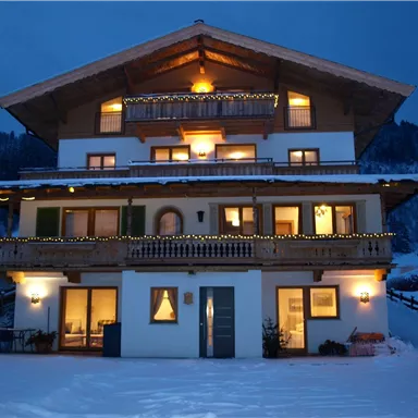 A cozy chalet in the snow with glowing windows. The surroundings are calm and wintry, ideal for a relaxing retreat.