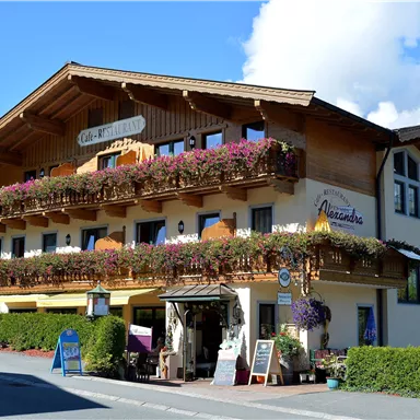 A beautiful, traditional house with a balcony full of flowers. The facade is bright and inviting, surrounded by well-kept greenery.