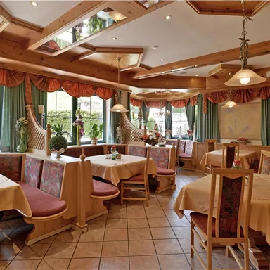 An inviting restaurant with wooden decor and large windows. The tables are set, and the atmosphere is cozy.