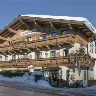 A charming mountain hotel with traditional architecture and wooden cladding. The surrounding snow and clear skies enhance the alpine atmosphere.