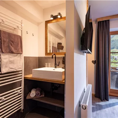 A modern bathroom with an elegant sink and towels. Through the window, there is a beautiful view of the mountains.