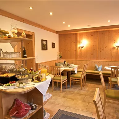 An inviting restaurant with wooden-paneled walls and tables. Various dishes are arranged on a buffet.