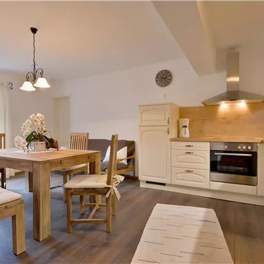 A modern kitchen with a wooden dining area. The space is bright and inviting, with a cozy atmosphere.