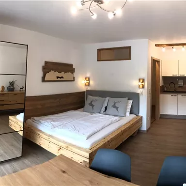 Ein modernes Schlafzimmer mit einem Doppelbett und Holzdekor. Der Raum ist hell erleuchtet und bietet eine gemütliche Atmosphäre.