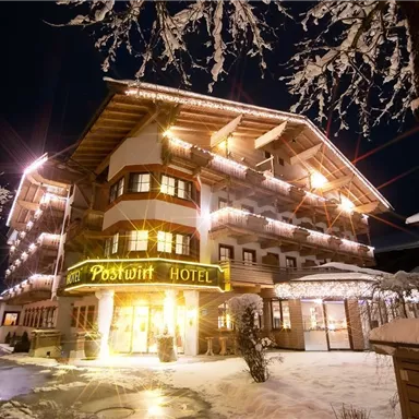A charming hotel in the snow, illuminated with warm lights. The winter landscape creates a cozy atmosphere.