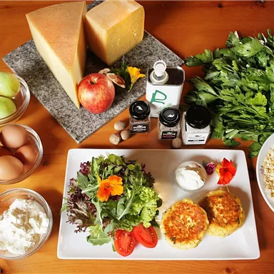 A beautiful table with fresh ingredients, including cheese, vegetables, eggs, and fruit. On the plate, there are salad and freshly prepared snacks.