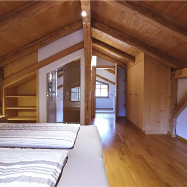 Ein gemütliches Zimmer im Dachgeschoss mit Holzdecken und einem modernen Design. Es gibt ein Doppelbett und viel Platz für Aufbewahrung.