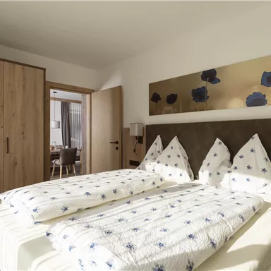 A modern bedroom with two beds and a spacious wardrobe. The walls are painted in light colors, and a piece of art adorns the wall above the bed.