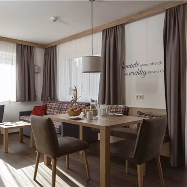 A bright, modern dining room with a wooden table and comfortable chairs. Large windows provide plenty of natural light and a cozy atmosphere.