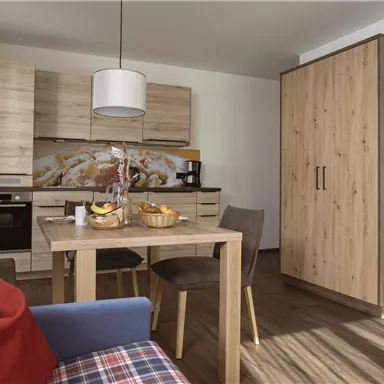 A cozy kitchen with modern furniture and a dining table. The room is designed to be bright and welcoming.
