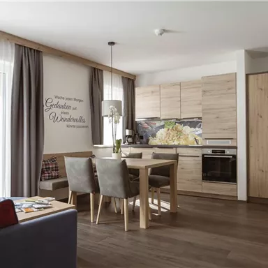 A cozy apartment with a modern kitchen and a dining area. Bright colors and wooden details create an inviting atmosphere.
