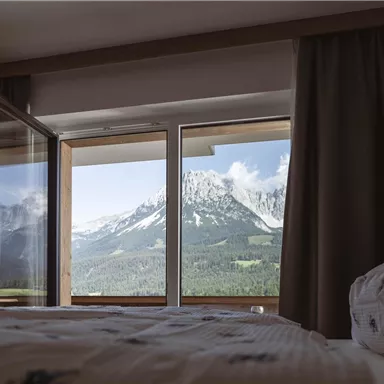 A cozy bedroom with a view of majestic mountains. The window opens to a beautiful landscape with a clear view.