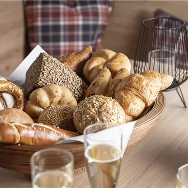 A pretty tray with various rolls and pastries. In the background, glasses and a banana are visible.