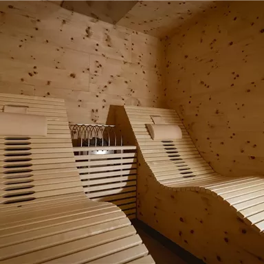 A relaxing room with two wooden lounge chairs. The walls are made of light wood, creating a calm atmosphere.